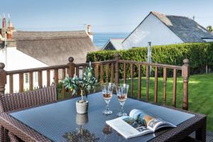 a table with wine glasses and a book on a balcony at Trevarrow Cottage in Coverack