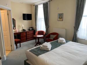 a bedroom with a bed and a desk and chairs at Peregrine House in Canterbury