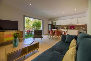 a living room with a blue couch and a kitchen at Les Pins de Santa Giulia in Porto-Vecchio