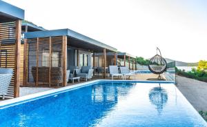 una piscina con sillas y una casa en Olivia Green Camping, en Tisno