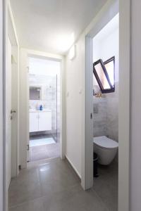 a white bathroom with a toilet and a sink at La Maison de Raphael in Netanya