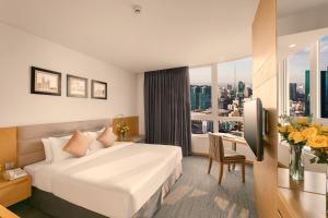 a hotel room with a bed and a desk and a window at Liberty Central Saigon Centre Hotel in Ho Chi Minh City