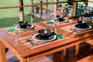 una mesa de madera con platos y copas de vino. en Guacimo Lodge, en El Castillo de La Concepción