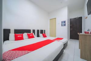 una camera da letto con un grande letto con cuscini rossi di OYO 89820 Sp Berlian Inn a Sungai Petani