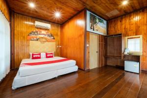 a bedroom with a large bed in a room with wooden walls at OYO 75336 Blue resort & spa in Ko Chang