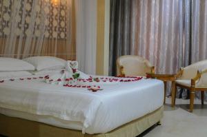 Una cama blanca con flores rojas encima. en Saab Royale Hotel, en Nairobi