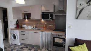 a kitchen with white cabinets and a sink and a washer at Grand Quevilly Centre Ville in Le Grand-Quevilly