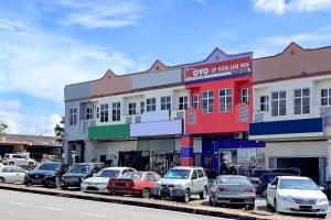 una fila di auto parcheggiate di fronte a un edificio di OYO 89820 Sp Berlian Inn a Sungai Petani