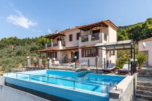 a villa with a swimming pool in front of a house at Villa Peparethos in Stafylos