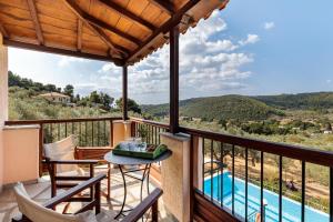 balcón con mesa, sillas y piscina en Villa Peparethos, en Stafylos
