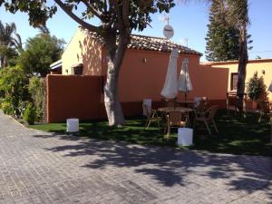 een patio met een tafel en stoelen en een parasol bij Apartamento para 4 personas con jardín privado y barbacoa cerca de la playa in Vejer de la Frontera