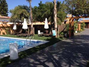 una piscina con sombrillas y sillas junto a una casa en Apartamento para 4 personas con jardín privado y barbacoa cerca de la playa en Vejer de la Frontera