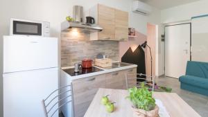małą kuchnię ze stołem i lodówką w obiekcie Babyaccommodation Family Panoramic II w mieście Pietra Ligure