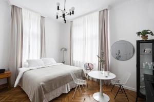 biała sypialnia z łóżkiem, stołem i krzesłami w obiekcie Wesoła Apartments w Krakowie