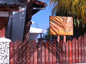 a red fence with a painting on it next to a palm tree at The Sunrise Huraa in Huraa