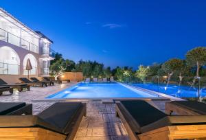 a large swimming pool with benches around a building at Litore Luxury Living in Laganas