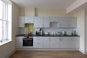 a white kitchen with white cabinets and a window at Apartment 7, Isabella House, Aparthotel, By RentMyHouse in Hereford