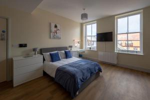 een slaapkamer met een bed met blauwe lakens en 2 ramen bij Apartment 7, Isabella House, Aparthotel, By RentMyHouse in Hereford