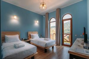 2 łóżka w pokoju z niebieskimi ścianami i oknami w obiekcie Hotel Chateau Iveri w mieście Varjanisi
