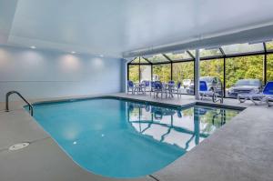 Comfort Inn & Suites Troutville - Roanoke North - Daleville في Troutville: مسبح في مبنى فيه كراسي ونوافذ