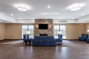 a lobby with a fireplace and a couch and chairs at Comfort Inn & Suites in Waller