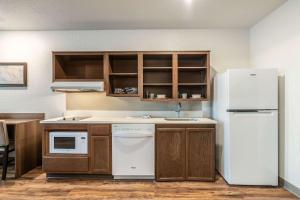 a kitchen with a white refrigerator and wooden cabinets at WoodSpring Suites Sanford North I-4 Orlando Area in Sanford