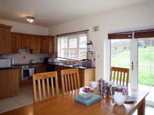 a kitchen with a wooden table and a table and chairs at Cois Chnoic Holiday Home Dingle by Trident Holiday Homes in Dingle +9 photos