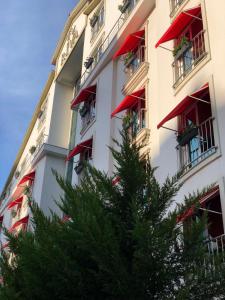 a building with red balconies and a tree in front of it at Riva Reşatbey Luxury Hotel in Adana