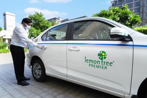 a man in a face mask washing a white lemon tree premier car at Lazy Lagoon, Baga A Lemon Tree Resort, Goa in Baga