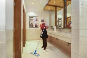 a woman with a mop in a bathroom at Lazy Lagoon, Baga A Lemon Tree Resort, Goa in Baga