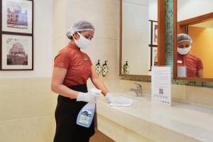 a woman wearing a mask standing in a bathroom sink at Lazy Lagoon, Baga A Lemon Tree Resort, Goa in Baga