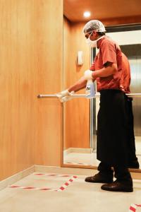 a woman is washing a door with a brush at Lazy Lagoon, Baga A Lemon Tree Resort, Goa in Baga