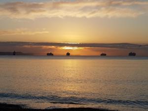 a sunset over the ocean with ships in the water at Seaspray Guest House in Weymouth
