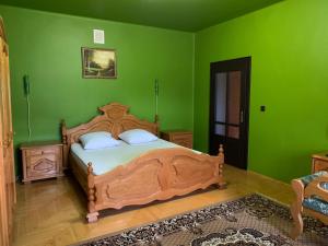 a bedroom with a wooden bed with green walls at Приватний будинок in Berehove