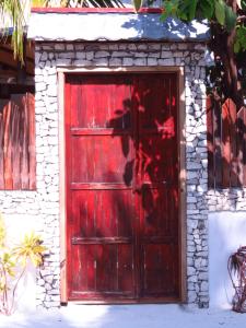 a red door in a building with a stone wall at The Sunrise Huraa in Huraa