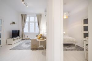 ein weißes Wohnzimmer mit einem Sofa und einem TV in der Unterkunft BpR LYNX Home with A/C in Budapest
