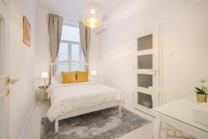 ein weißes Schlafzimmer mit einem Bett und einem Fenster in der Unterkunft BpR LYNX Home with A/C in Budapest