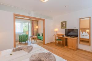 a hotel room with a bed and a desk and a television at Sport & Familienhotel Bärenwirt in Aich