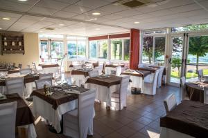 un restaurante con mesas, sillas blancas y ventanas en Logis Hôtel - Auberge du Pastel - Hôtel 3 étoiles et Restaurant, en Nailloux