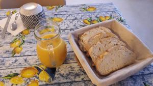 un tavolo con una pagnotta di pane e un bicchiere di succo d'arancia di Les TREMIERES a Saint-Paul-des-Fonts