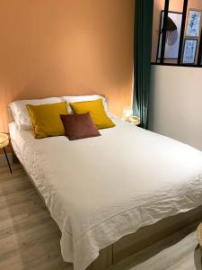 - un grand lit blanc avec des oreillers jaunes dans l'établissement Maison Britannia au cœur de Biarritz, à Biarritz