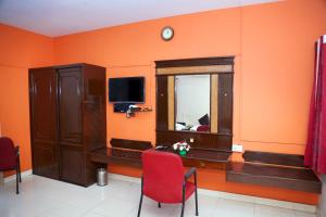 a room with an orange wall with a desk and a window at DAFFODILS SERVICED APARTMENT in Chennai