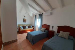 a bedroom with two beds and a couch at Casa Rural Finca las Tejoneras in Bornos