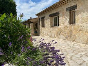 een stenen gebouw met paarse bloemen ervoor bij VILLA EN PIERRE in Vence