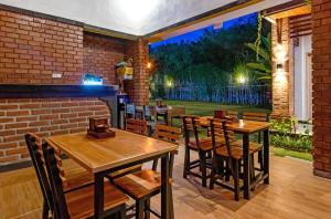 a restaurant with wooden tables and chairs and a brick wall at La Sari Village in Canggu