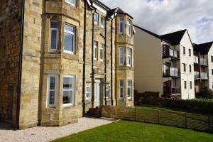 an old brick building with a grass yard in front of it at Beach house no2 with amazing sea views and private garden onto beach. in Fairlie