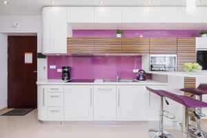 een keuken met witte kasten en paarse muren en krukken bij Apartament Neapol Rezydencja Sienkiewicza by Renters in Zakopane