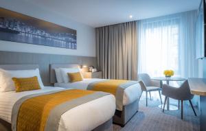 a hotel room with two beds and a table at Maldron Hotel Belfast International Airport in Aldergrove +25 photos