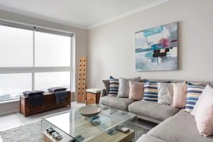 a living room with a couch and a glass table at Stunning Views, the Sea & Table Mountain! in Bloubergstrand