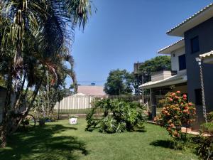 une cour avec un palmier et une maison dans l'établissement Pousada das Orquideas Foz, à Foz do Iguaçu